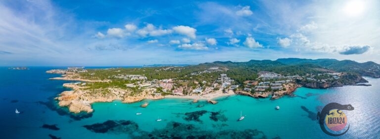 Aerial view of Cala Tarida showcasing its turquoise waters, sandy beach, and surrounding cliffs