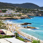 Cala Tarida beach with sunbeds, restaurants, and blue sea in Ibiza.