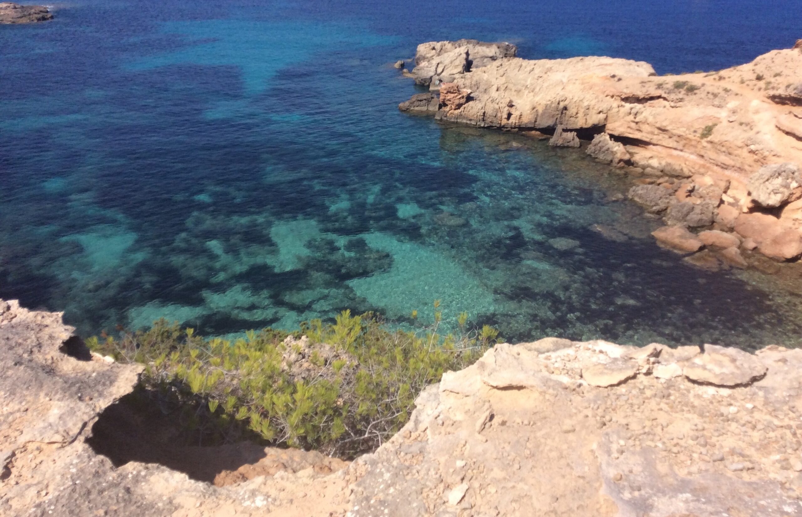 S'Illot des Renclí beach with rugged coastline, Ibiza, clear waters and rocky landscape