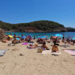 Sunlit Ibiza beach in April with clear skies and calm waves